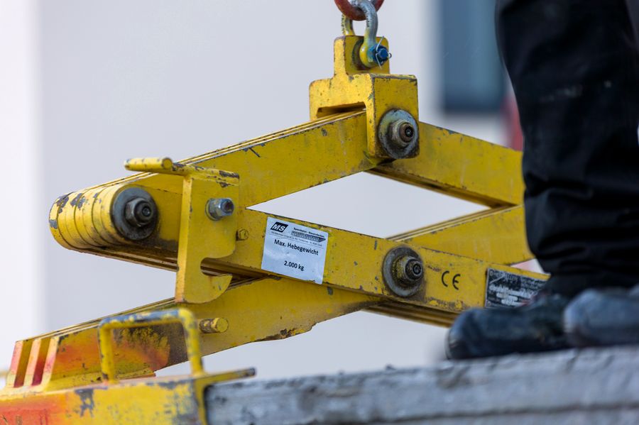 Monteur sichert Spannbeton-Hohlplatte bei der Verlegung